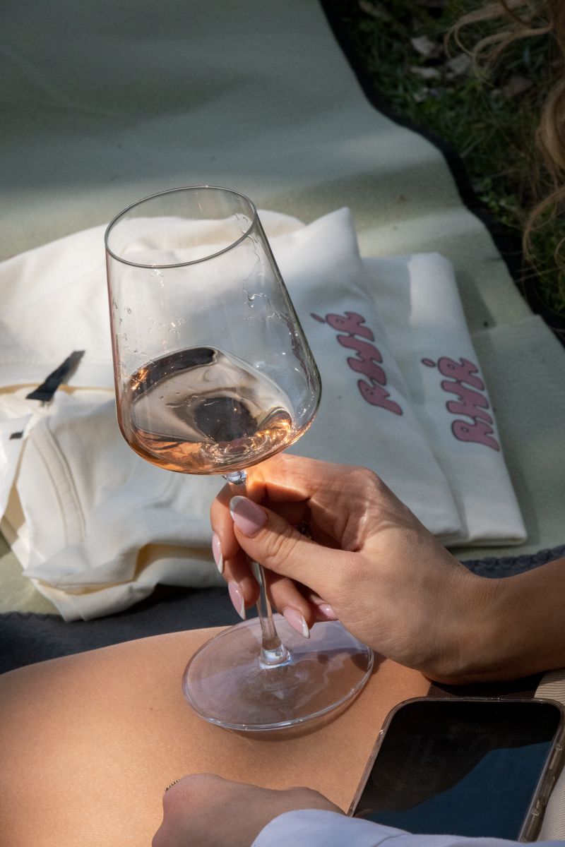 Eine junge Frau hält ein Glas Roséwein.