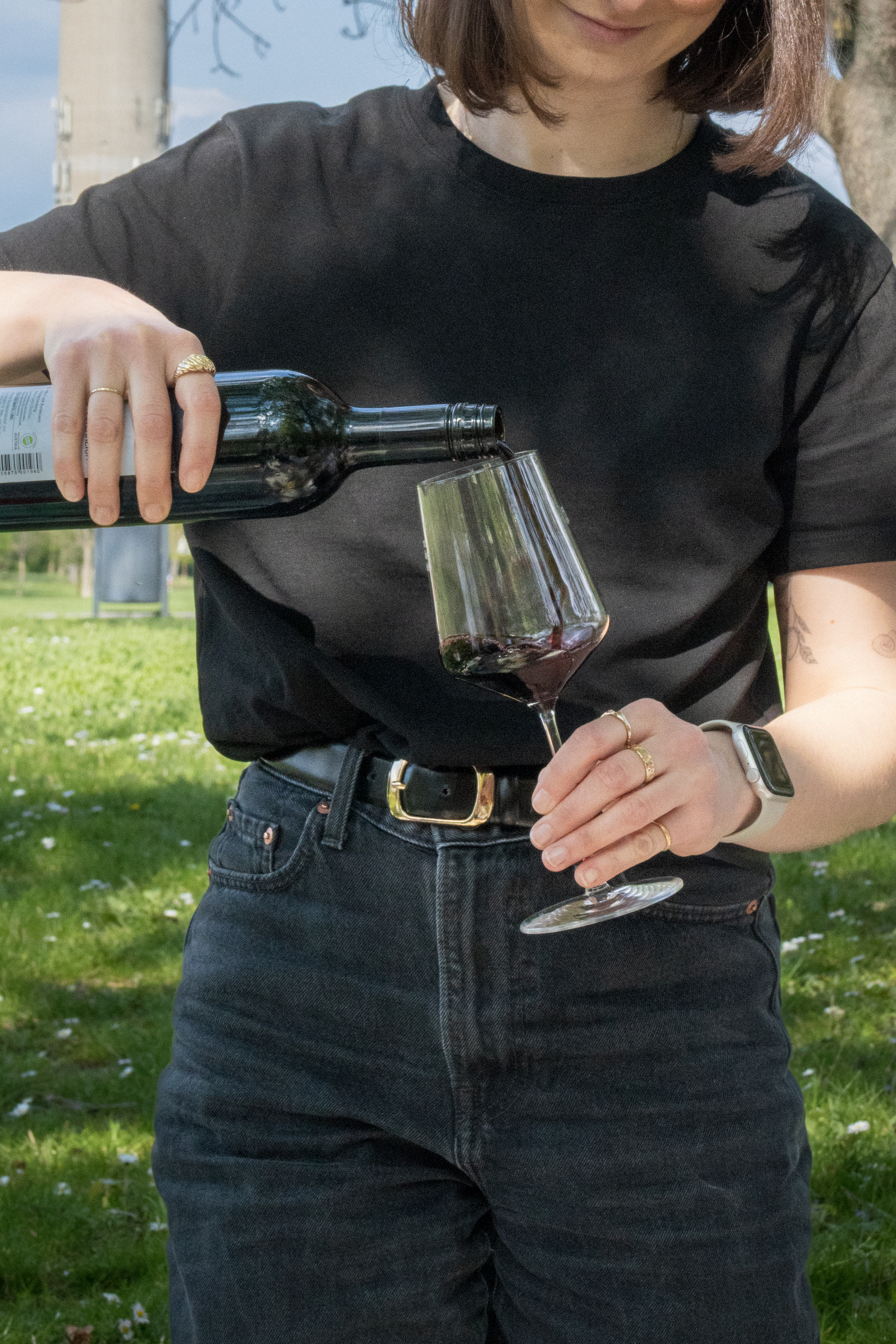Eine junge Frau schenkt sich Rotwein ein.