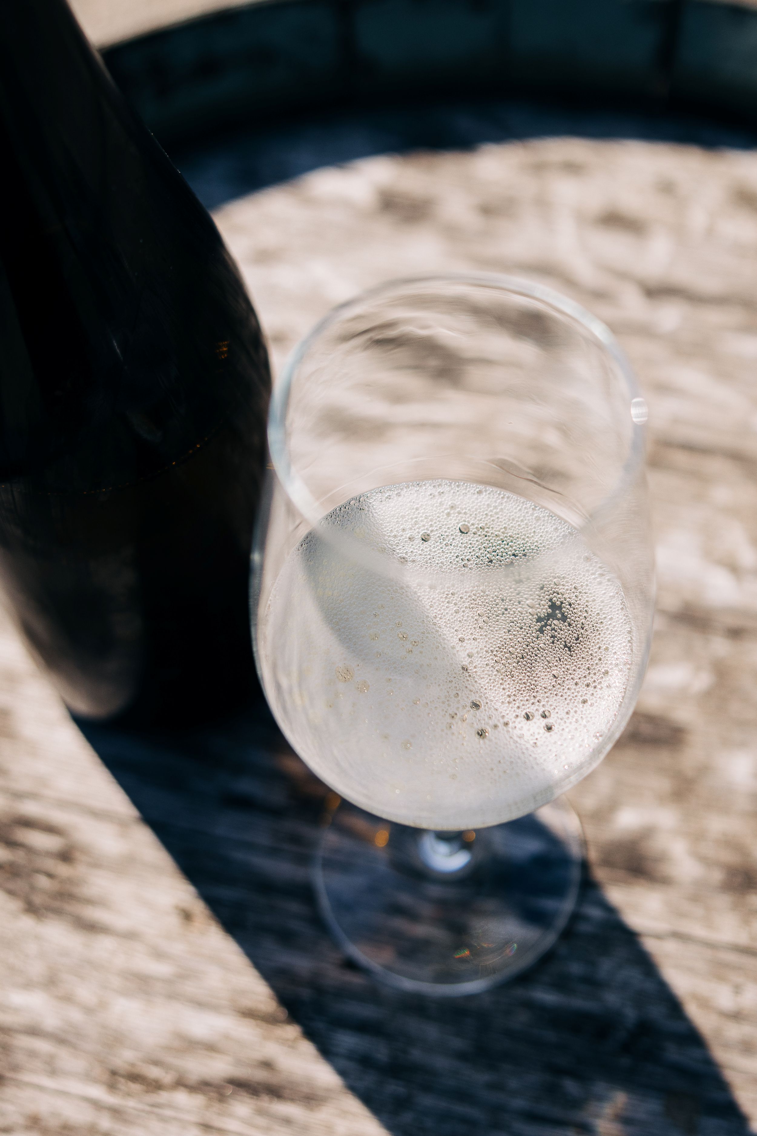 Ein Bild zeigt ein Glas voll Sekt im Sonnenlicht.