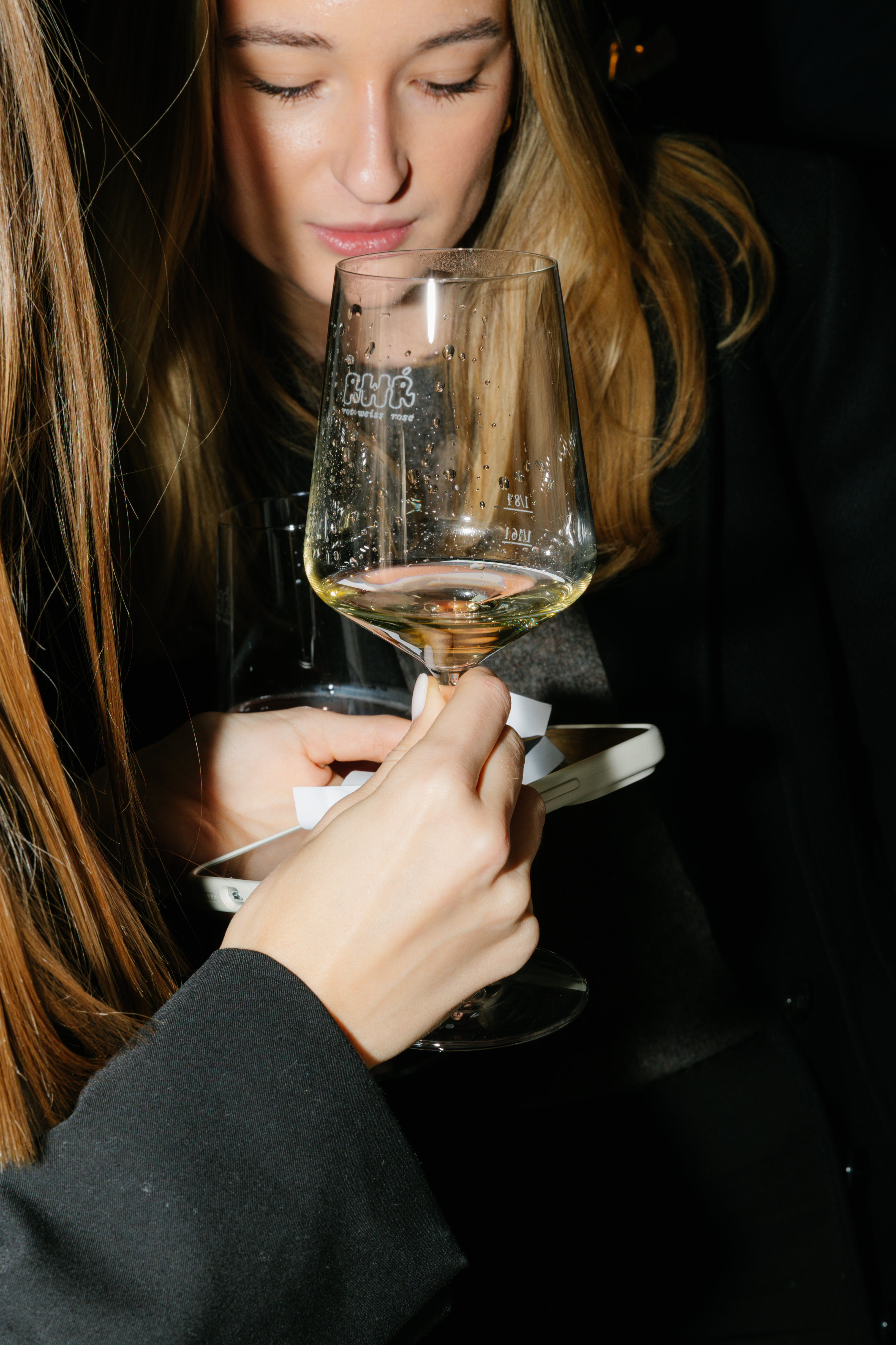 Eine junge Frau riecht an Weißwein.