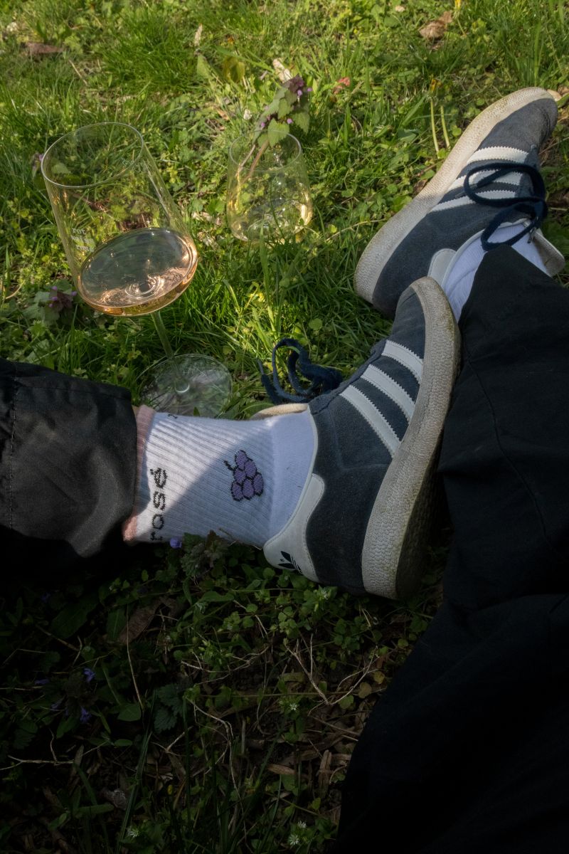 Eine Person sitzt im Gras mit einem Glas Rosé.