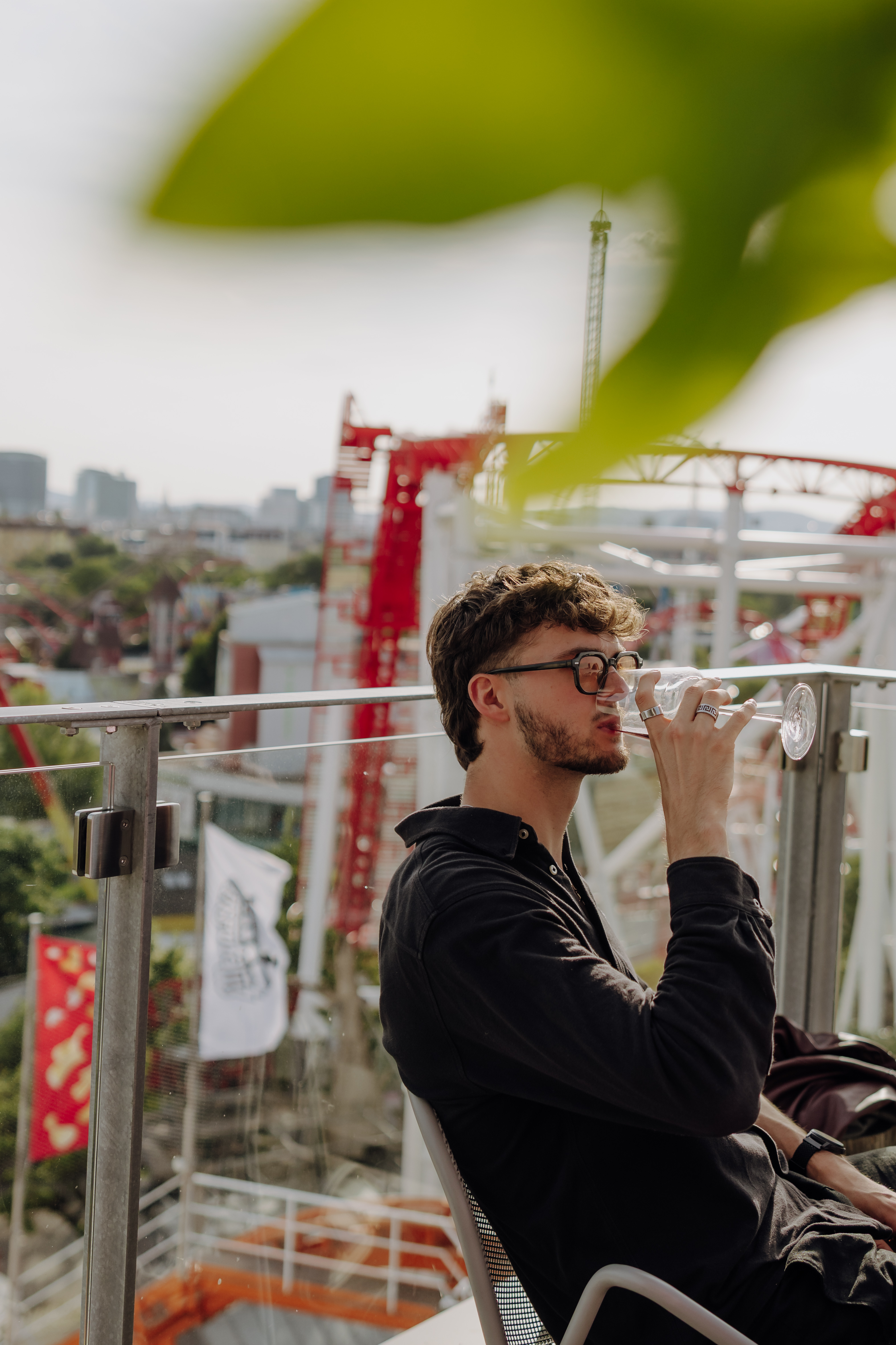 Ein junger Mann trinkt Rotwein in einer Rooftop-Bar.