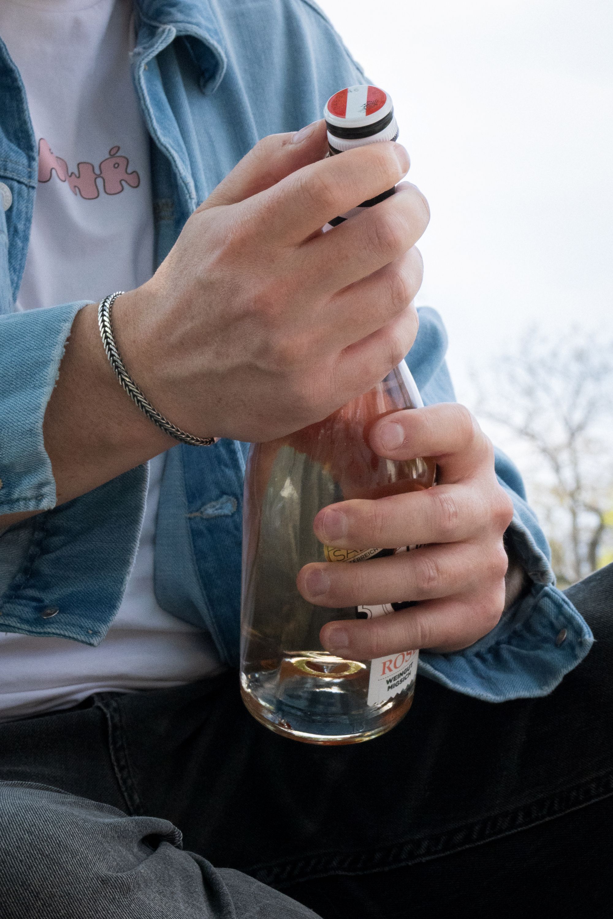 Ein junger Mann öffnet eine Flasche Rosé aus Österreich.