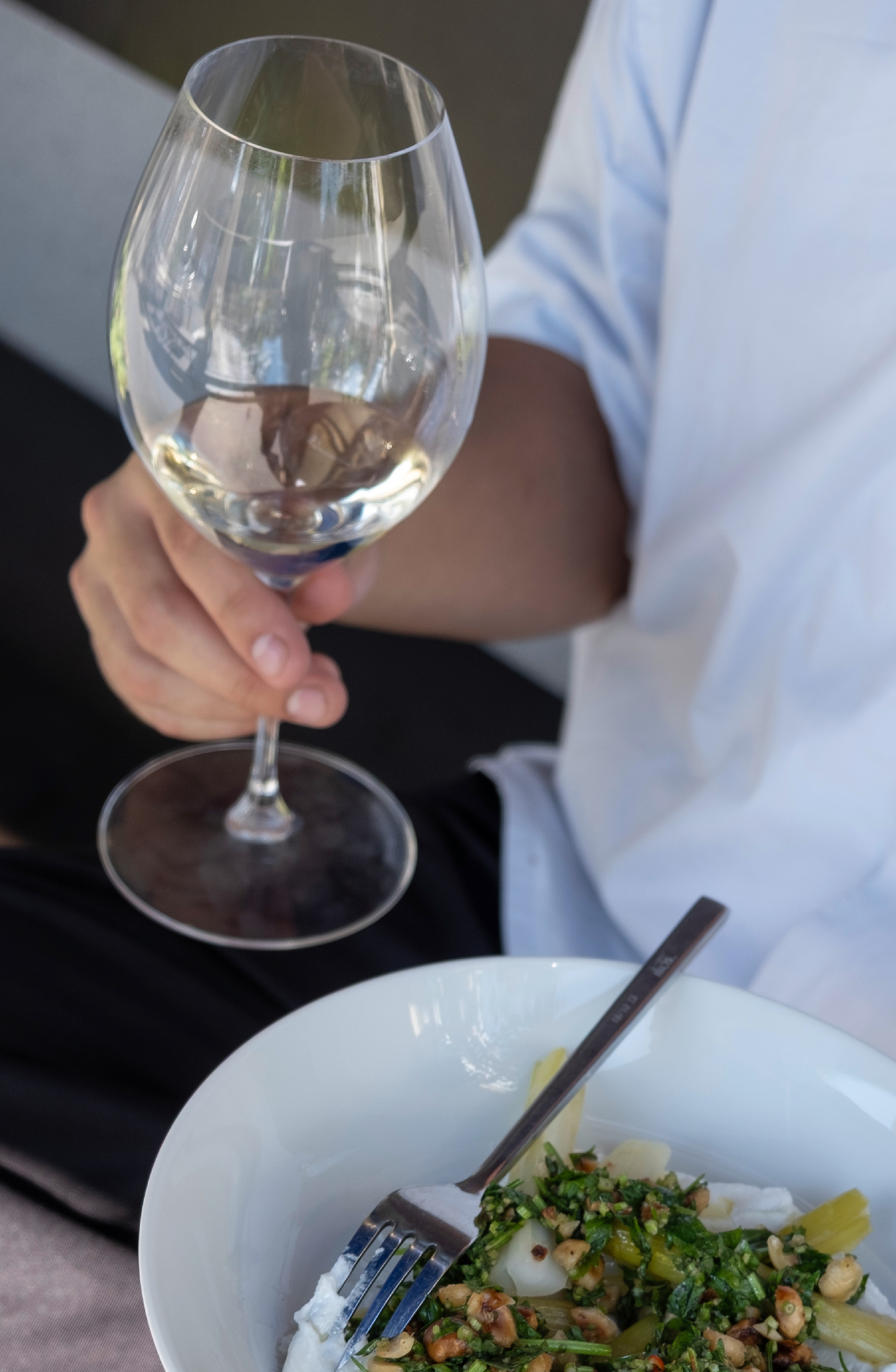 Das Bild zeigt einen jungen Menschen, der Riesling trinkt und Labneh isst.