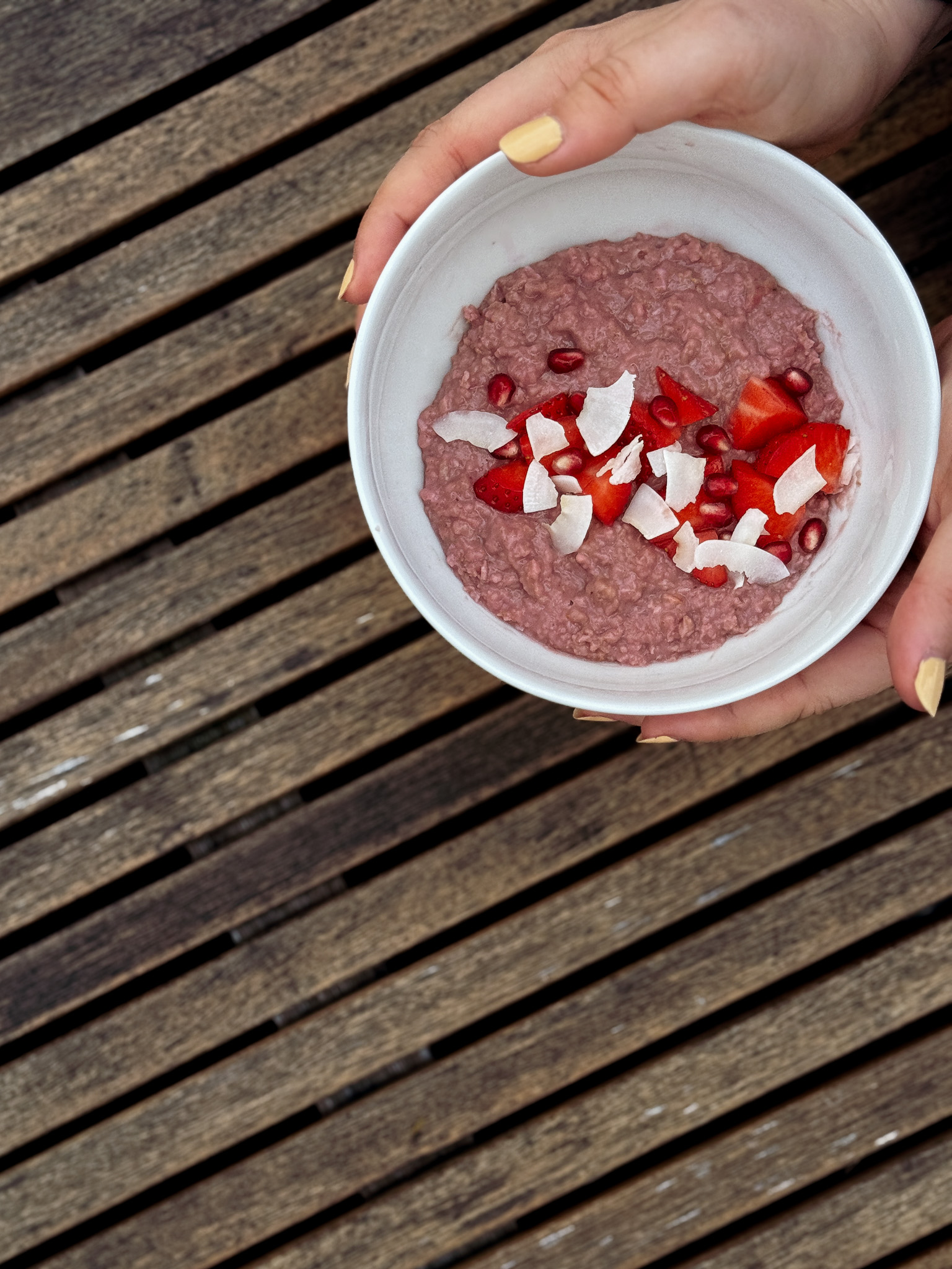 Eine junge Frau hält eine Schüssel Erdbeer-Porridge.