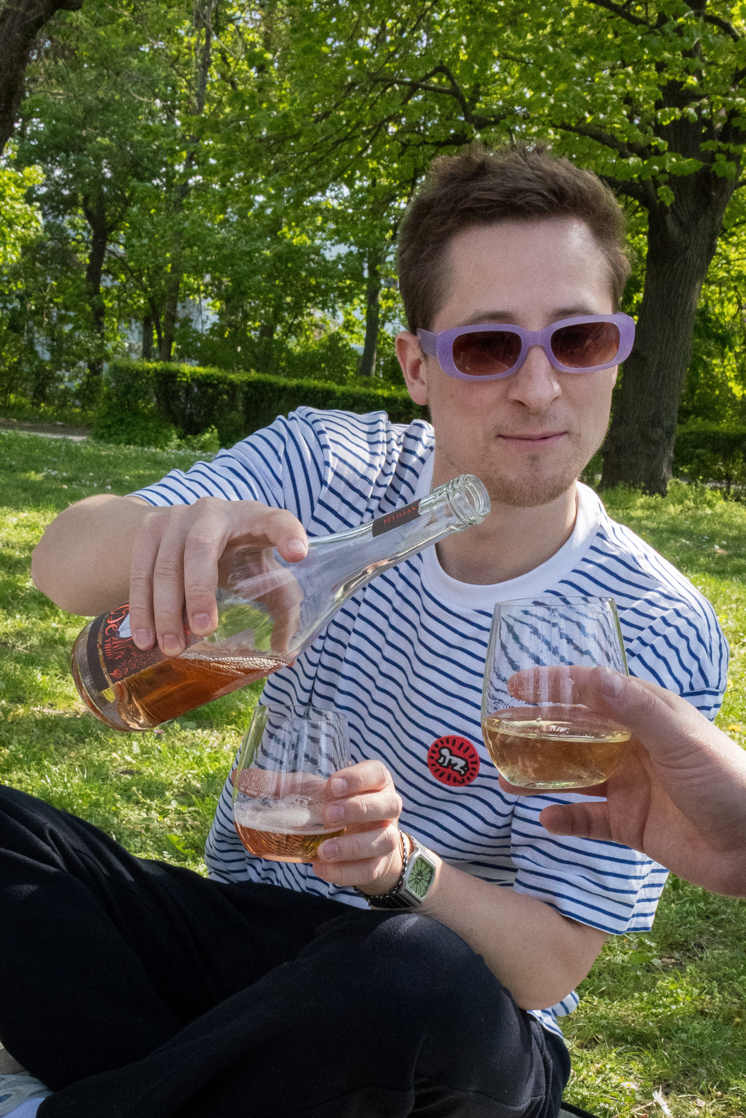 Ein junger Mann schenkt Rosé ein.