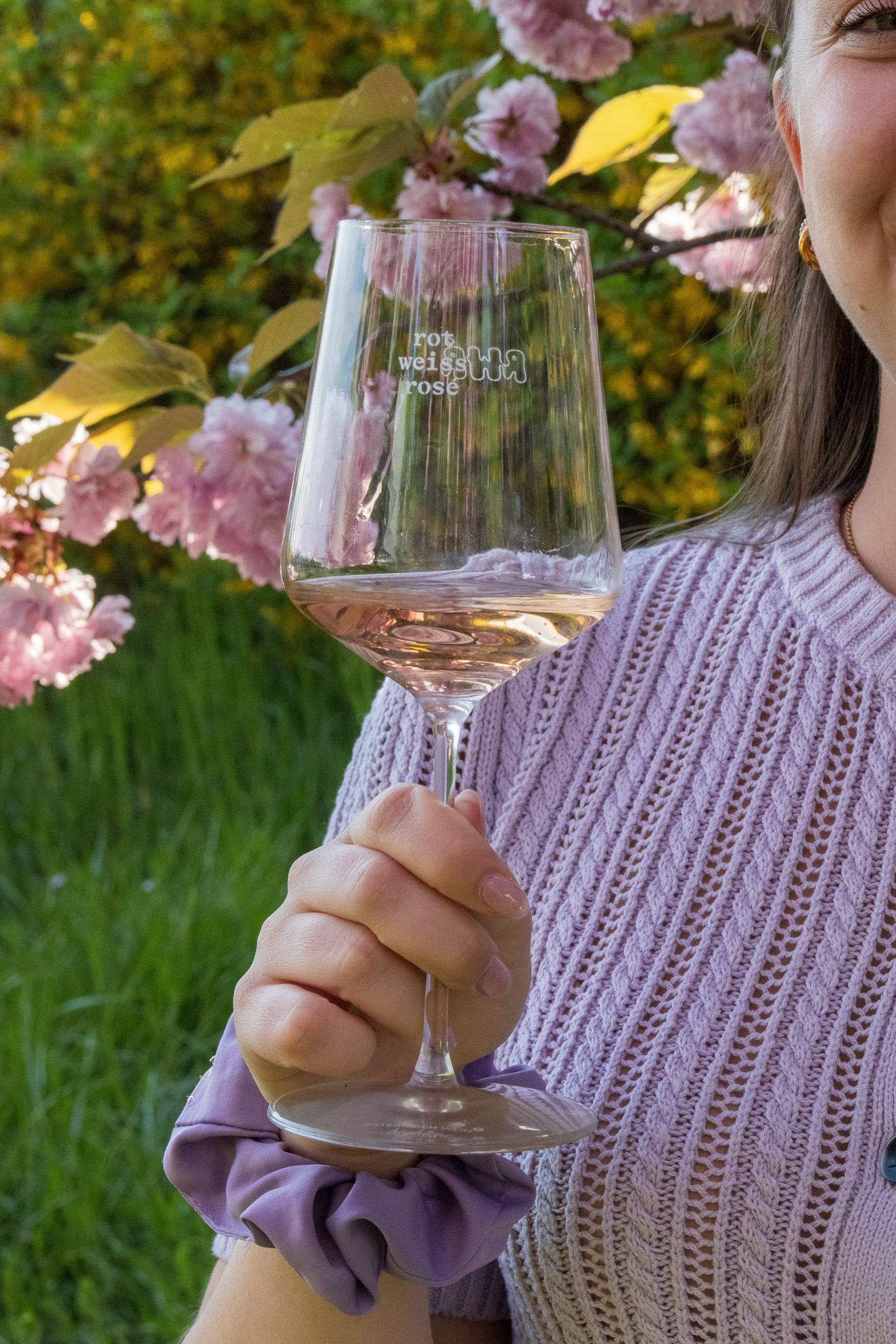 Eine junge Frau hält ein Glas Rosésekt.